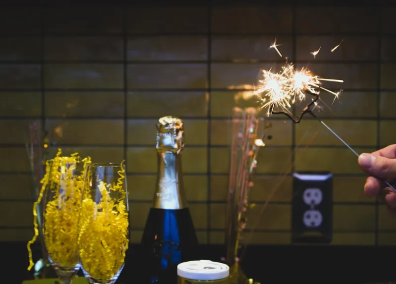 a person holding a sparkler next to a bottle of champagne